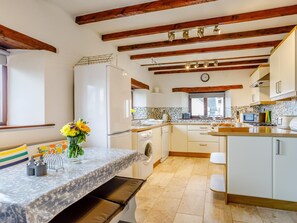Una cocina moderna con vigas de madera, lavadora integrada y zona de comedor con banco.