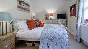 Un dormitorio con cama, mesitas de noche, televisor y obras de arte en las paredes.