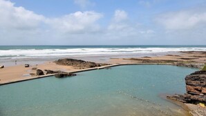 Eine Küstenlandschaft mit blauem Himmel, Strand und ruhigem Gewässer.