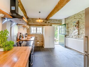 A kitchen with a stone wall, wooden beams, a stainless steel range hood, and a window. - 4 Bed in Cardigan (oc-79046) (Ponthirwaun)