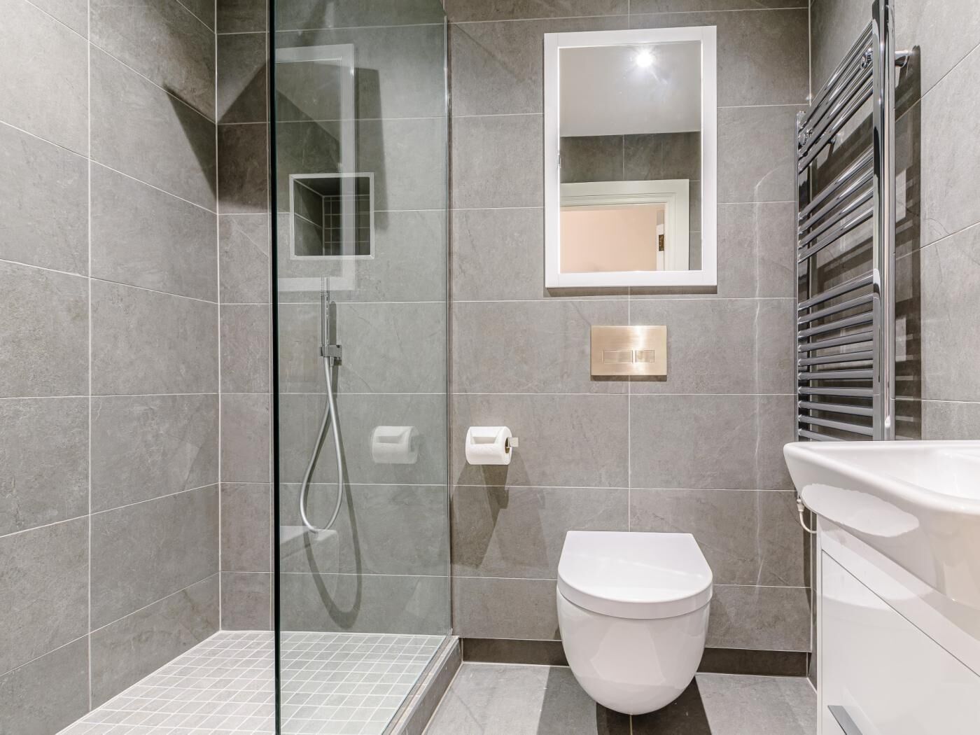 Ein modernes Badezimmer mit einer gläsernen Duschkabine, einer Toilette und einem integrierten Waschbecken.