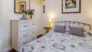 Een slaapkamer met een bed, een kaptafel, een spiegel, een lijst met een foto en een bedlamp.