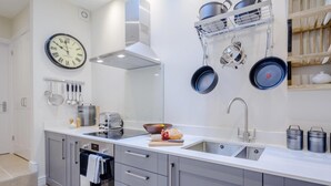 Eine moderne Küche mit Einbauofen, Dunstabzugshaube aus Edelstahl, einer Spüle und einer Uhr an der Wand.