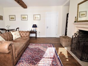 A living room with a brown leather sofa, a patterned rug, a fireplace, and framed pictures on the wall. - 1 Bed in Tetbury (oc-79151) (Tetbury)