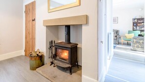 A room with a wood-burning stove, a wooden door, and a mirror on the wall. - 3 Bed in Richmond (oc-79275) (Kiplin)