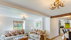 A living room with two sofas, a coffee table, and a dining table with chairs. There is a kitchen visible in the background. - 2 Bed in Driffield (oc-79280) (Wold Newton)