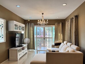 A living room with a sofa, TV, white cabinet, and a fan. - Simple and Private Living Home near Suvarnabhumi Airport 23 min (บางโฉลง)