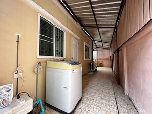 Una lavanderia con lavatrice, scaldabagno e un tubo collegato a una presa a muro.