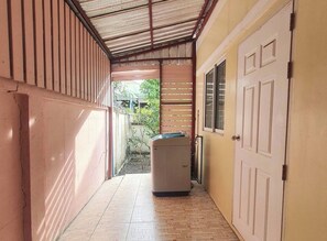 A corridor with a tiled floor, a door on the right, and a small appliance in the center. - Simple and Private Living Home near Suvarnabhumi Airport 23 min (บางโฉลง)