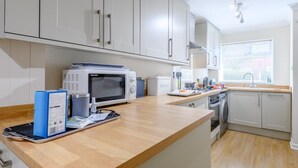 A modern kitchen with white cabinets, a microwave, a coffee maker, and a sink. - 1 Bed in Lymington (oc-79332) (Milford on Sea)