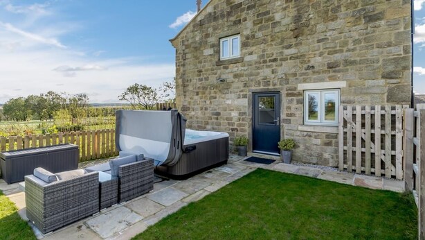 A stone building with a small porch, a hot tub, and outdoor seating. - 1 Bed in Harrogate (oc-79400) (Felliscliffe)