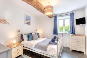 A bedroom with a bed, bedside tables, a TV, and a window with curtains. - 6 Bed in Petrockstow (oc-79407) (Petrockstow)