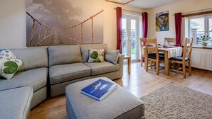 A living room with a sofa, ottoman, dining table, chairs, and a painting on the wall. - 2 Bed in Torrington (oc-79483) (Langtree)