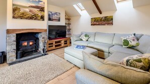 A cozy living room with a stone fireplace, a flat-screen TV, a sofa, and a ceiling with skylights. - 2 Bed in Torrington (oc-79483) (Langtree)