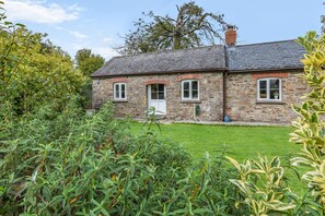 A stone house with a sloped roof, a front door, and windows. - 2 Bed in Torrington (oc-79483) (Langtree)