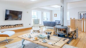 A spacious living room with a high ceiling, a fireplace, a television, and a comfortable seating area. - 4 Bed in Dunoon (oc-79529) (Ardentinny)