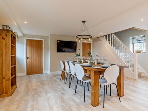 A dining area with a wooden table, white chairs, and a chandelier. - 5 Bed in Leek (oc-79543) (Grindon)