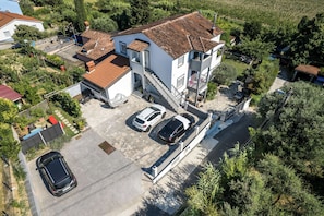 A two-story building with a tiled roof, a covered parking area, and a staircase leading to the upper floor. - Villa Bazilika (Piran)