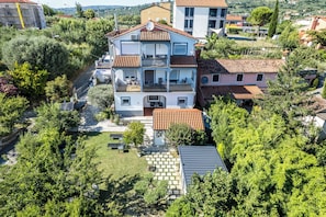 Um edifício residencial de vários andares com varandas, um jardim e um caminho de acesso pavimentado.
