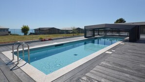 A swimming pool with a wooden deck, a covered seating area, and a view of the ocean. - 2 Bed in Brixham (oc-79989) (Brixham)