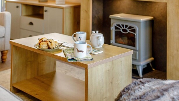Une pièce chaleureuse avec une table en bois, une tasse blanche, une théière et une assiette de pâtisseries.