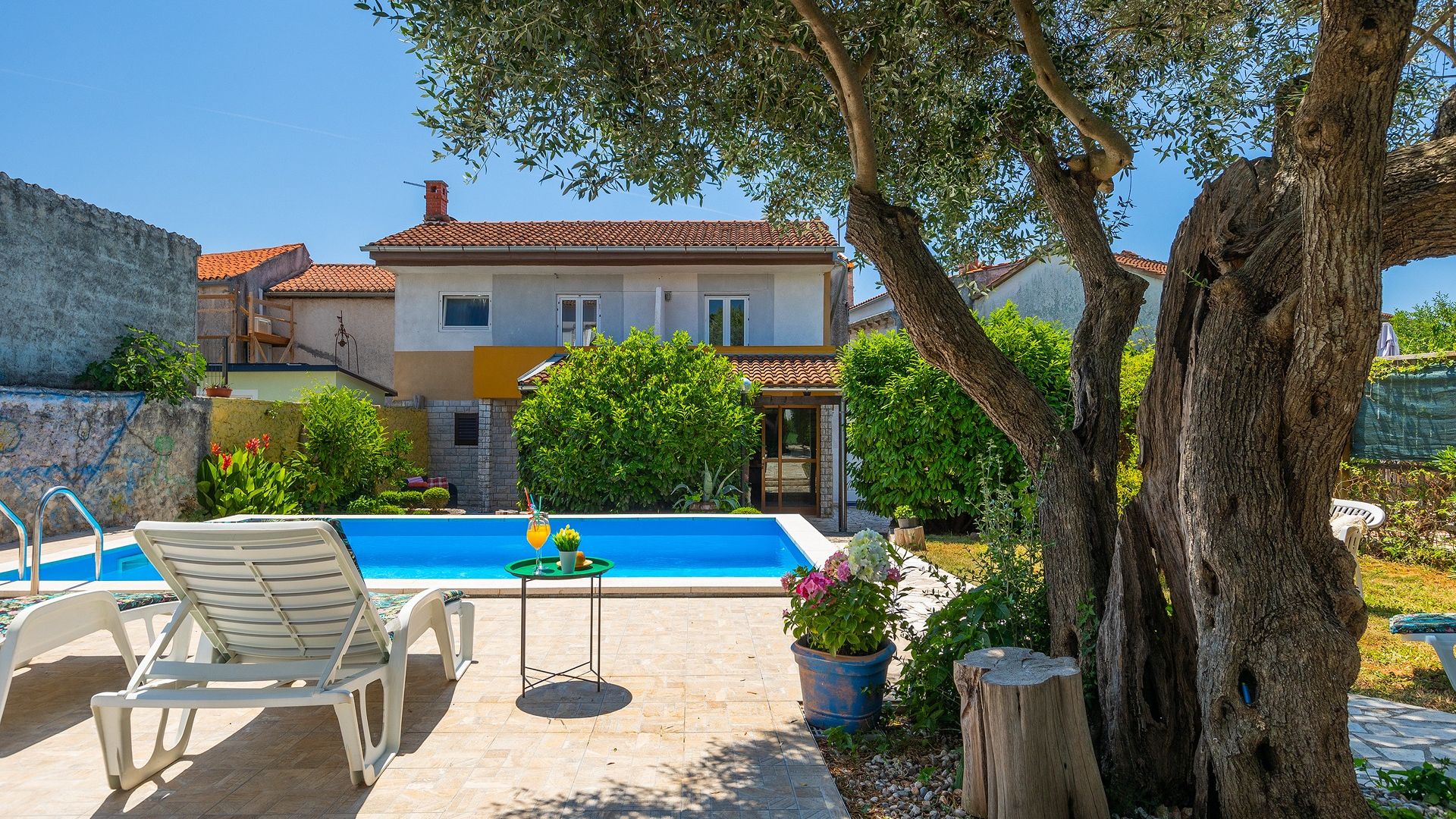 Une villa avec piscine, un espace salon extérieur et un jardin.