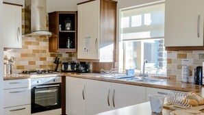 Cocina moderna con estufa, horno y pileta. Una ventana provee luz natural.