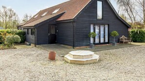 Een donker houten gebouw met schuin dak en een klein veranda.