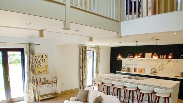 Een moderne keuken met een marmeren aanrecht, barkrukken en hanglampen.