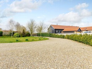 A gravel driveway leading to a house with a red roof, surrounded by a well-maintained lawn and hedges. - 3 Bed in Ipswich (oc-80545) (Needham Market)