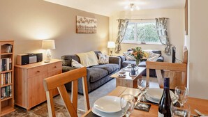 A cozy living room with a sofa, a dining table set for two, and a bookshelf. - 2 Bed in Abergele (oc-80629) (Gwytherin)