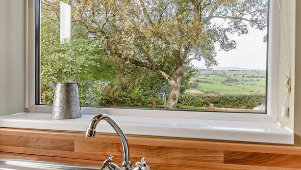 A kitchen with a window view of a tree and countryside. - 2 Bed in Abergele (oc-80629) (Gwytherin)