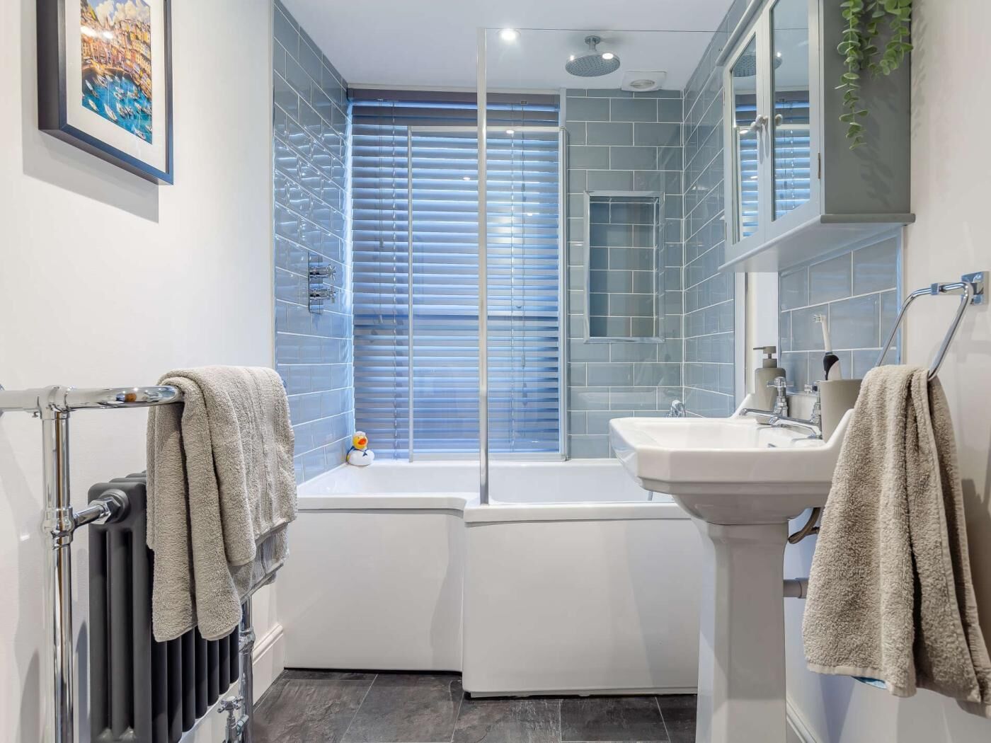 A modern bathroom with a bathtub, a sink, and a radiator.