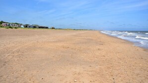 En sandstrand med en rad strandhytter och en klar himmel.
