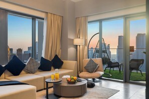 A modern living room with a sofa, coffee table, and chairs, large windows with curtains, and a view of the city skyline. - Spacious 3.5BR Burj LED View High Floor  (Dubai)