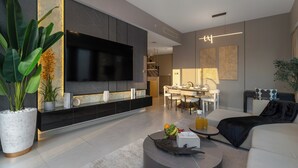 A modern living room with a flat-screen TV, a dining area with a table and chairs, and a kitchen in the background. - Spacious 3.5BR Burj LED View High Floor  (Dubai)