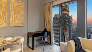 A modern room with a dining table, a chair, a sofa, a large window with a city view, and a potted plant. - Spacious 3.5BR Burj LED View High Floor  (Dubai)