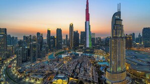 A cityscape with a prominent skyscraper, a curved building, and a river. - Spacious 3.5BR Burj LED View High Floor  (Dubai)