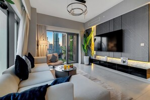 A modern living room with a sofa, coffee table, and a flat-screen TV mounted on the wall. - Spacious 3.5BR Burj LED View High Floor  (Dubai)