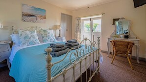 Ein Schlafzimmer mit Bett, Nachttisch, Stuhl, Kommode, Spiegel und einer Deckenleuchte.