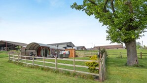 A farm with a barn, a covered outdoor seating area, and a fenced pasture.