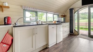 A kitchen with a window, a kettle, a microwave, and a dishwasher.