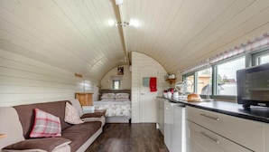 A compact RV interior with a kitchenette, a bed, and a seating area.