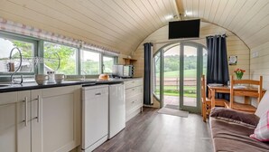 A compact kitchen with a sink, a toaster, and a window with curtains.