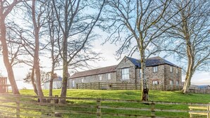 A stone building with a sloped roof, surrounded by a wooden fence and trees. - 1 Bed in Launceston (oc-81332) (Saint Giles on the Heath)