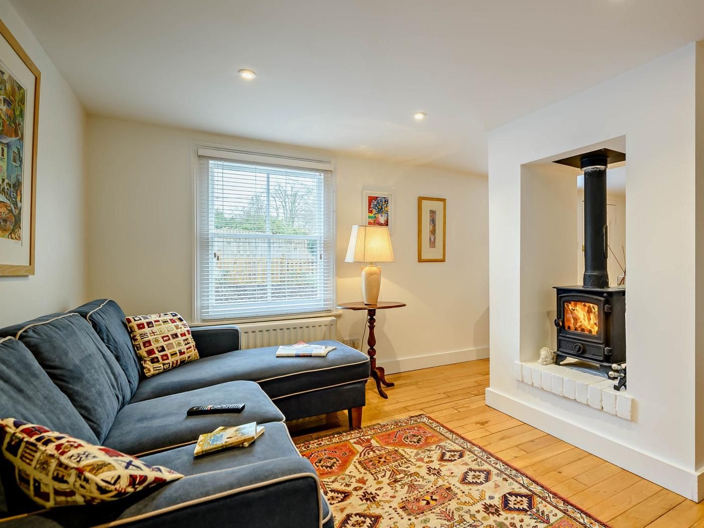 A living room with a sofa, a fireplace, a window with blinds, and a rug.