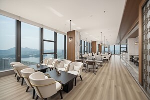 Uma sala de conferências moderna com grandes janelas, uma mesa comprida e várias cadeiras.