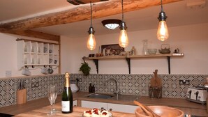 Et køkken med en træø, hængende lamper og en vinflaske.