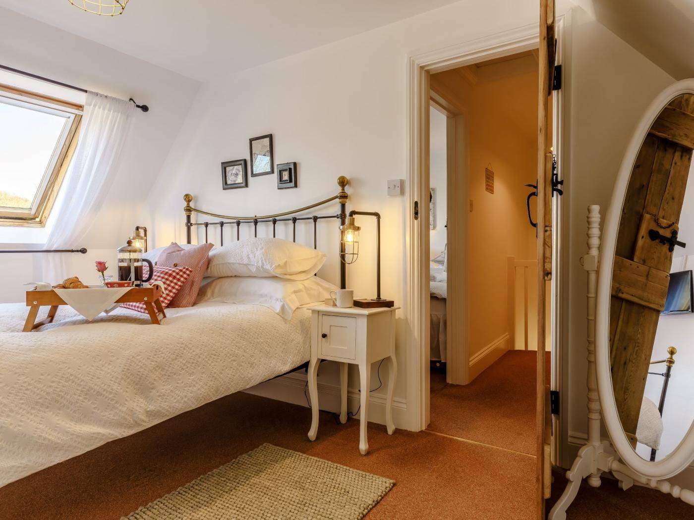 A bedroom with a bed, bedside table, lamp, and a mirror.