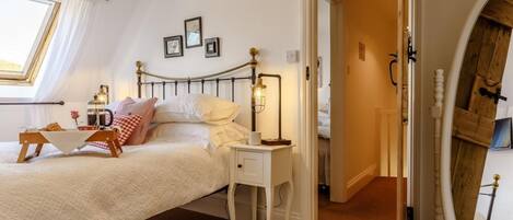 A bedroom with a bed, bedside table, lamp, and a mirror.